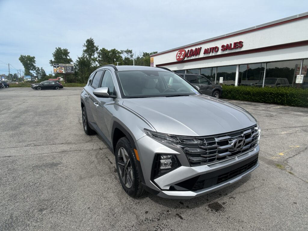 Silver SUV in a dealership parking lot in front of EZ Auto Sales under a blue sky