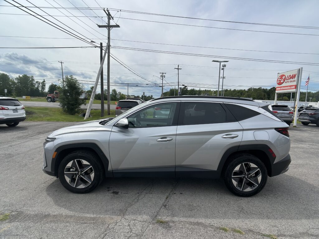 Silver SUV in a dealership lot with power lines overhead and an EZ Loans Auto Sales sign in the background.