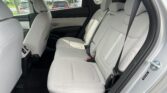 Rear seats of a light gray car interior, front seats visible, with seat belts fastened and outside vehicles seen through the windows.