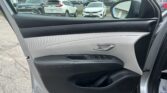 Open car door interior with black and gray panels; outside parking lot visible with white SUV and other cars under a partly cloudy sky.