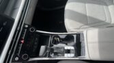 Interior of a car showing the front seats and center control panel with the gear shifter, cup holders, and climate controls in view.