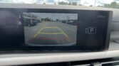 Infotainment screen showing a rearview camera view with colored guiding lines (red, yellow, green) for parking in a dealership lot