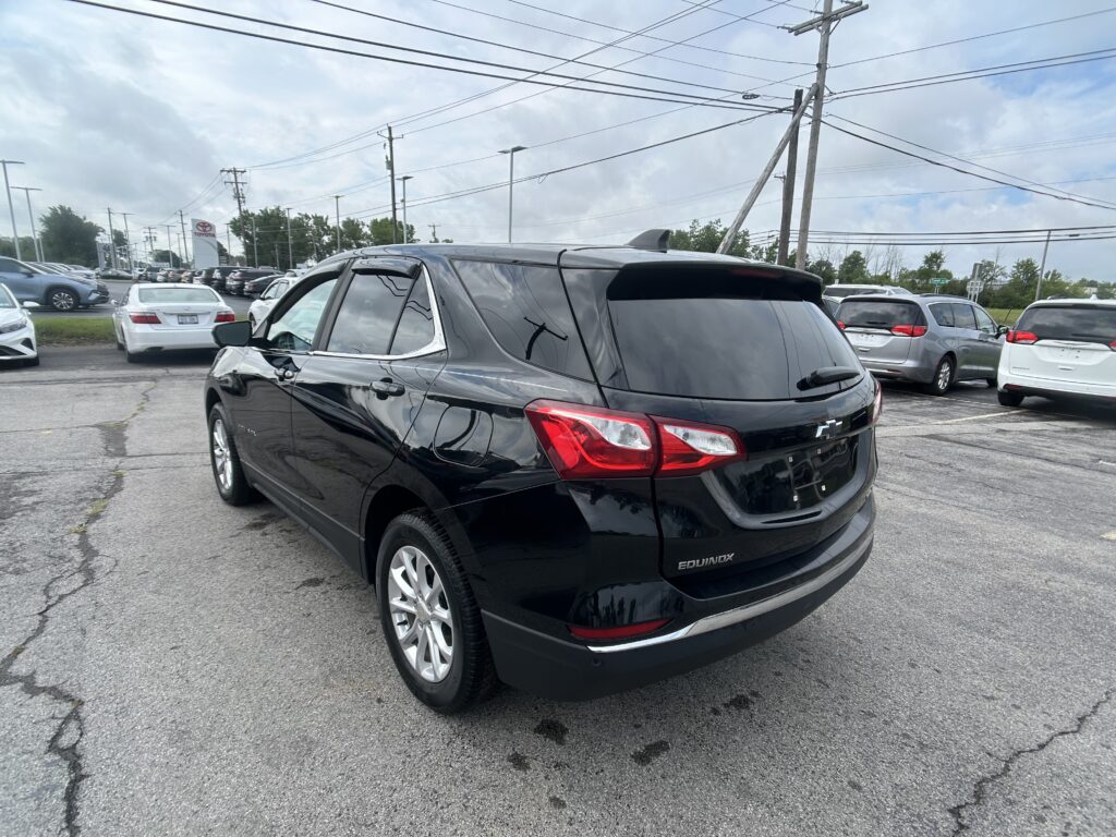 Black Chevrolet Equinox parked in a car dealership lot with other cars and power lines overhead