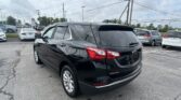 Black Chevrolet Equinox parked in a car dealership lot with other cars and power lines overhead