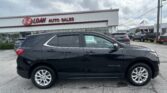 Black Chevrolet Equinox in the foreground at an E-Z Loan Auto Sales lot with other cars and a dealership building in the background