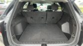 Open SUV rear hatch showing a spacious cargo area with folded/fixed rear seats and dark carpeting