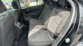 Rear seats of a car with black fabric upholstery and quilted pattern, three headrests, and visible seat belts.