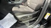 Front car interior showing driver seat and center console with a red seatbelt buckle visible, papers on the floor mat nearby
