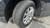 Close-up of a car tire and wheel under a dark SUV fender.