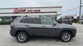 Gray Jeep Cherokee SUV in the foreground outside E-Z Loan Auto Sales; red E-Z LOAN sign on a white building.
