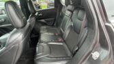 Rear interior of a car with black leather seats, three headrests, and visible seat belts.