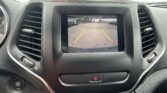 Center console touchscreen showing rearview camera with green, yellow, and red guide lines in a parking lot.