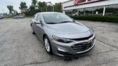 Front-left view of a silver Chevrolet sedan parked in a lot in front of EZ LOAN AUTO SALES storefront.