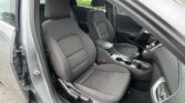Open-car-door interior of a gray sedan, showing the front seats, center console, and steering wheel partly visible.