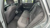 Rear passenger seats in a dark cloth interior sedan, headrests and seat belts visible from the open rear door.