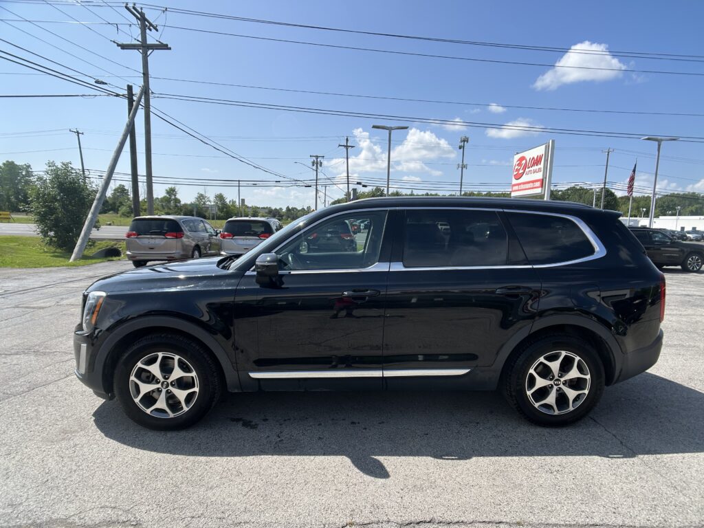 Black SUV parked in a car dealership lot with power lines overhead and an EZ LOAN Auto Sales sign in the background.
