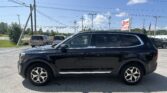 Black SUV parked in a car dealership lot with power lines overhead and an EZ LOAN Auto Sales sign in the background.