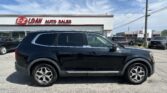 Black SUV parked in front of an auto sales lot with the E-Z LOAN AUTO SALES sign and blue sky above.
