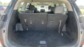 Open SUV rear cargo area with the third-row seats upright and black upholstery, showing empty trunk space behind them.