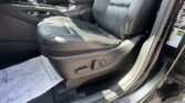 Front car interior showing black leather driver and passenger seats, center console with gear shifter, and door panel visible from the open car door.