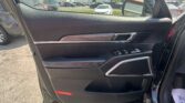 Inside view of a car door panel: black textured surface with wood trim, chrome handle, and control buttons near the armrest.