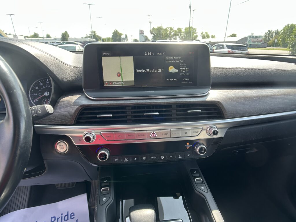 Interior of a car dashboard with a wide touchscreen showing a map/navigation on the left and weather status on the right (Radio/Media Off).