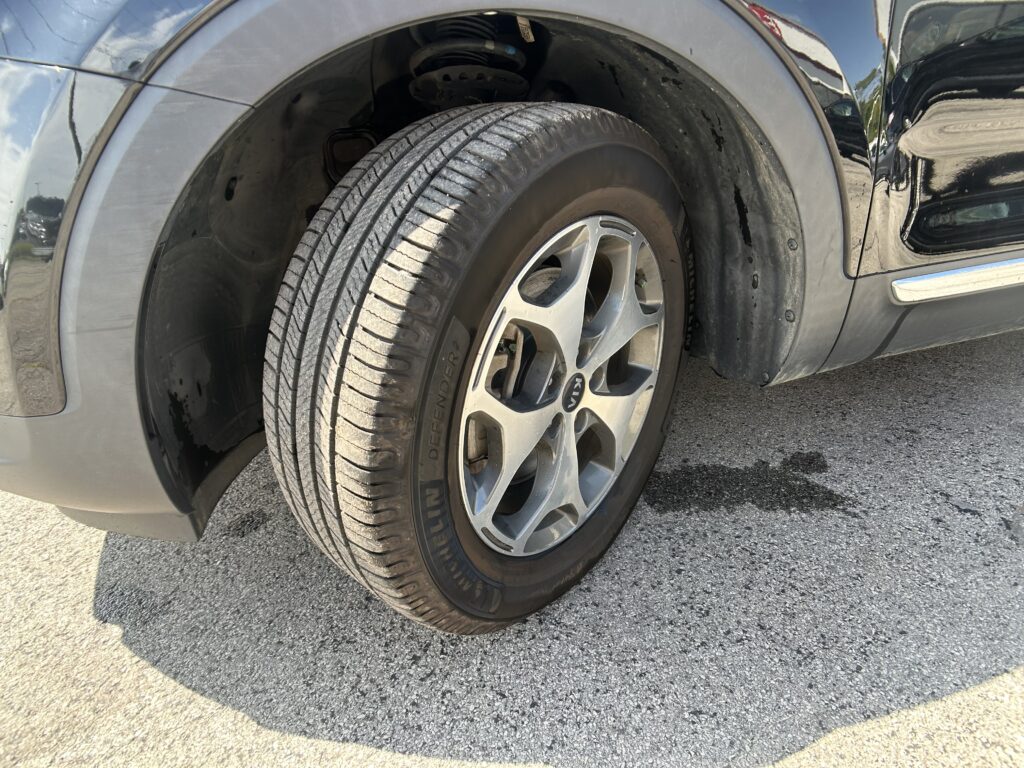 Close-up of a car's front wheel and tire, showing the alloy rim and wheel well.