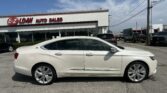 White sedan in the foreground at EZ Loan Auto Sales with a red sign on a white building and a blue sky above.