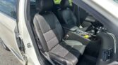 Open driver-side car door revealing black leather front seats with orange stitching and a center console visible inside the vehicle.