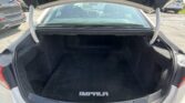 Open car trunk with a spacious black carpeted cargo area; trunk lid raised, rear window view into cabin, 'IMPALA' floor mat visible at the edge of the trunk.