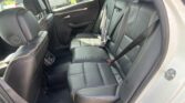 Rear passenger row in a black leather car with orange stitching and visible seat belts