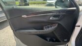 Close-up of a car's dark interior door panel showing window controls, chrome door handle, and Bose speaker; parking lot visible outside.