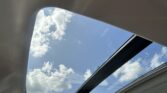 View through a car sunroof showing blue sky and white clouds