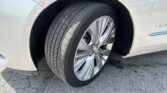 Close-up of a car's front wheel and tire with a silver alloy rim and light-colored body panel visible
